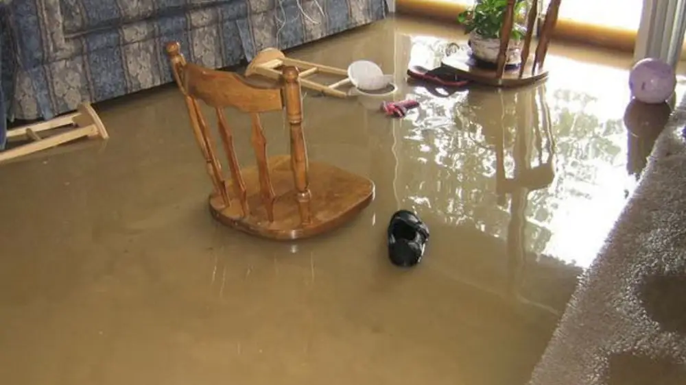 Room with a chair and belongings sitting in floodwater